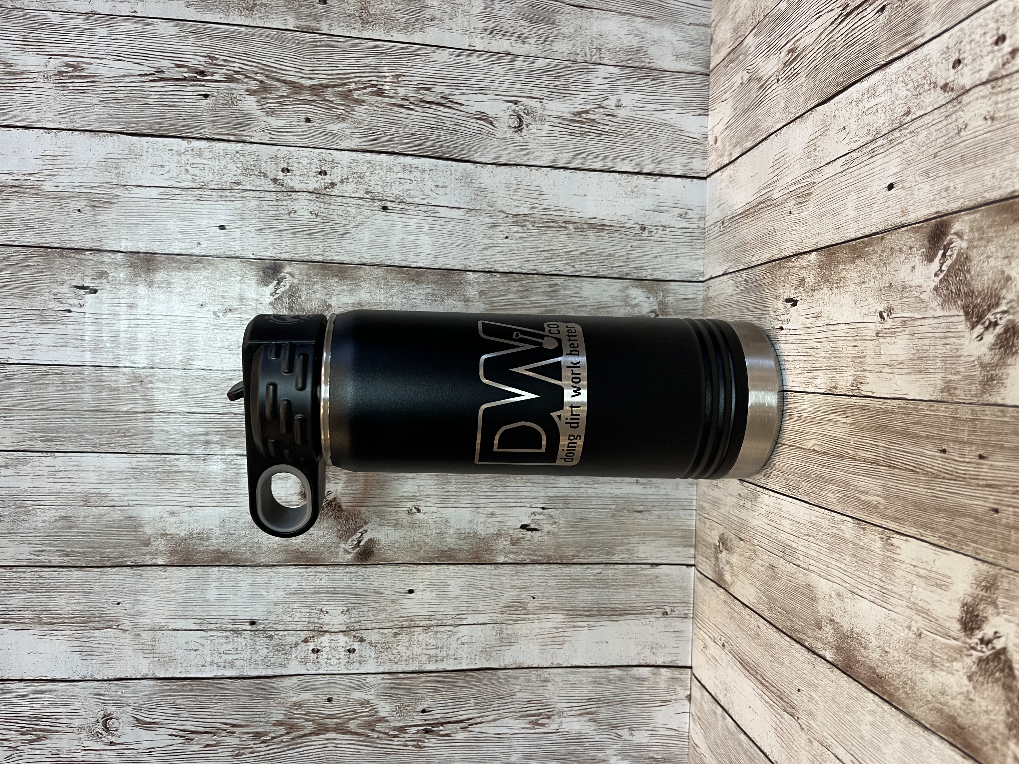 A black thermos sitting on top of a wooden table.
