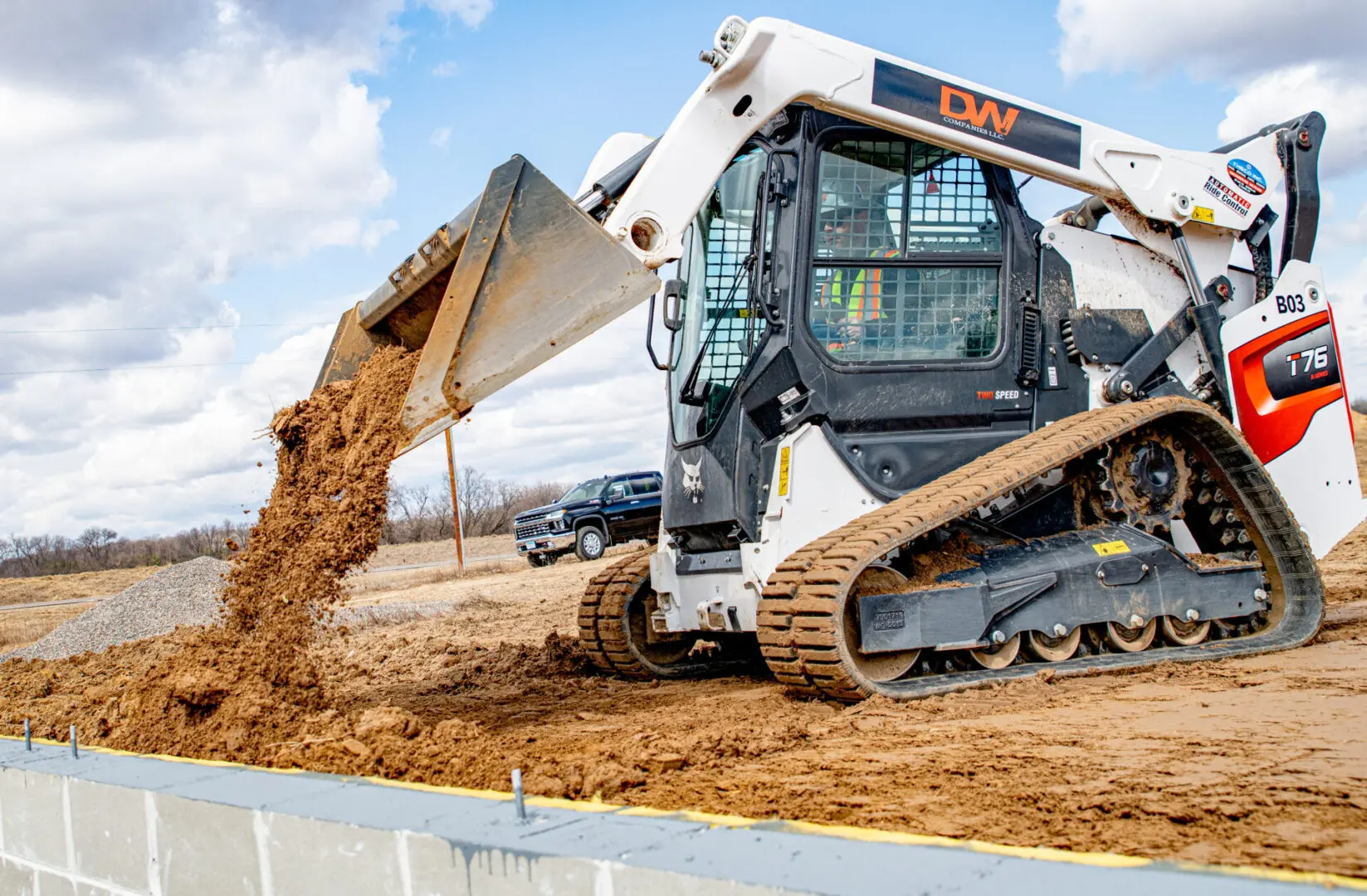 A white and black tractor is digging dirt