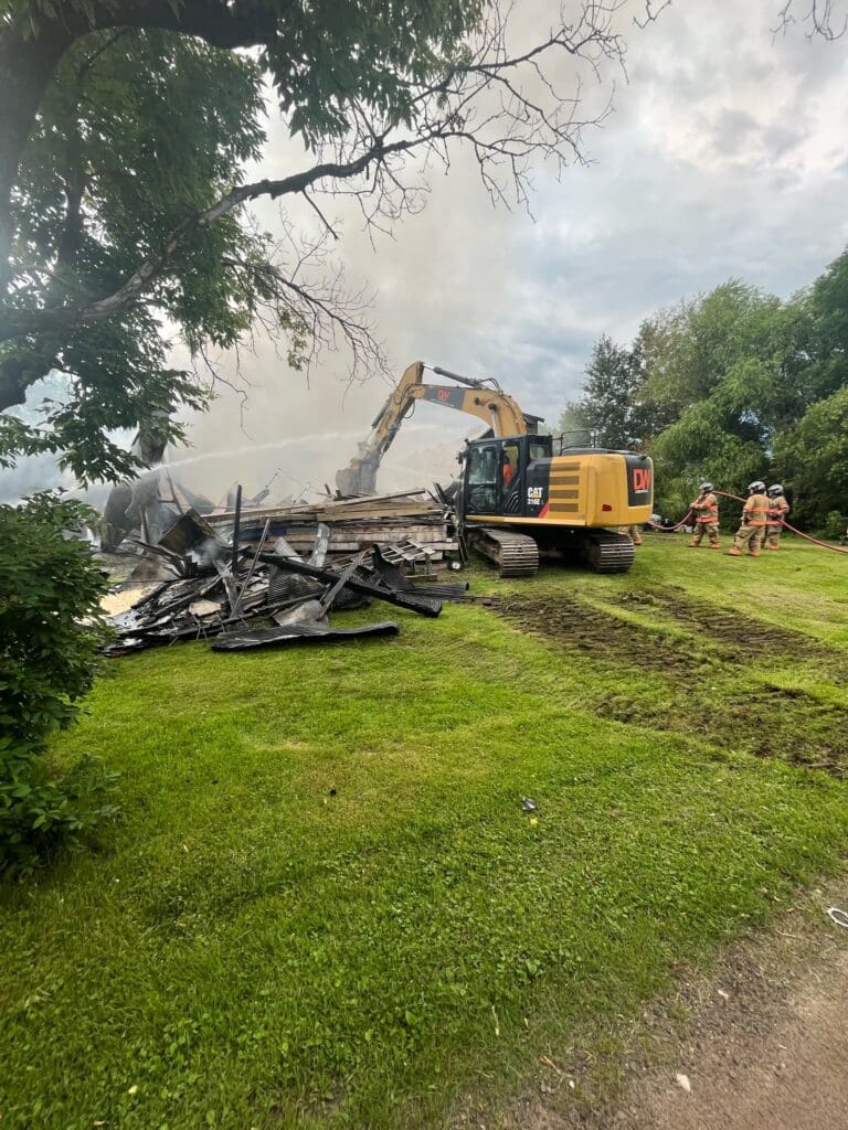 excavator assisting firefighters in a house fire 