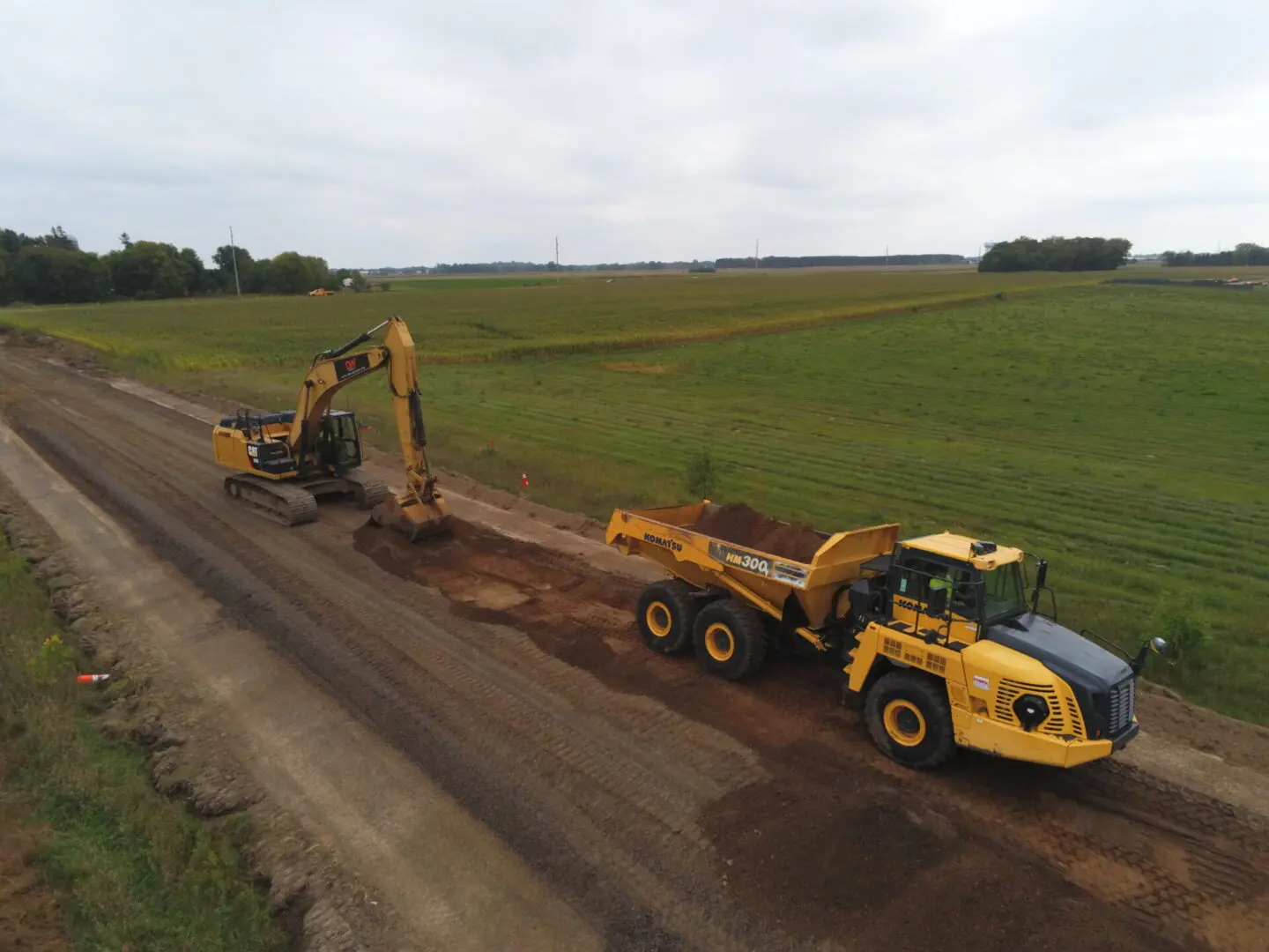 an excavator and off road dump truck excavating and hauling dirt at a road project 