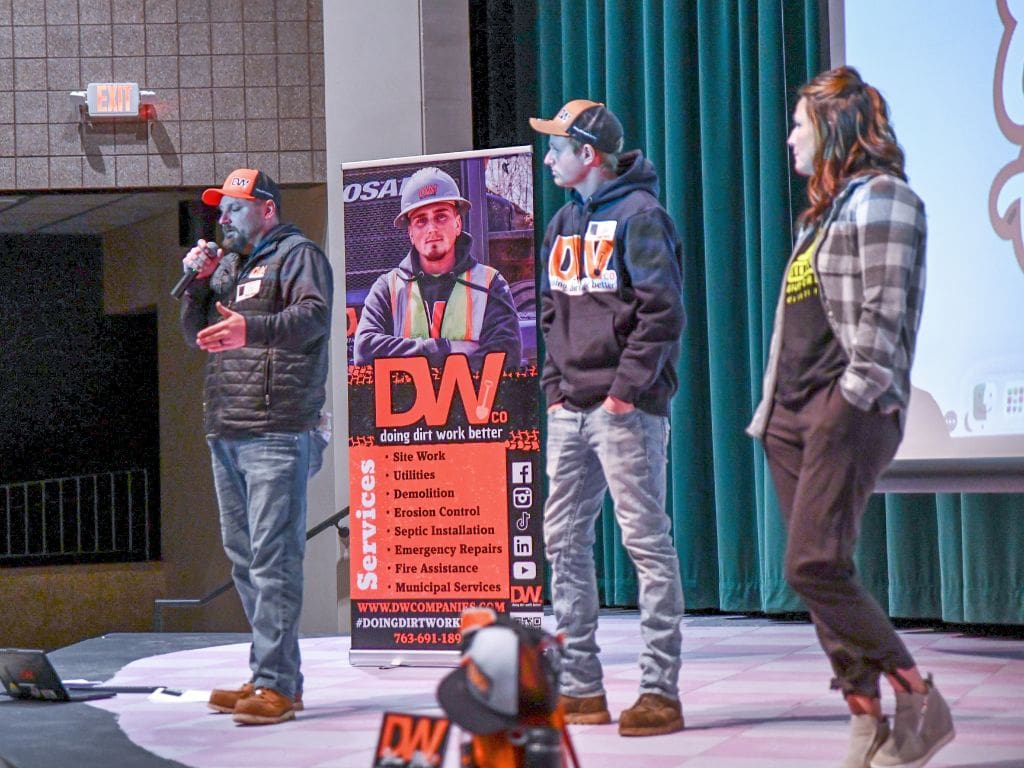 A group of people standing on stage with a banner.