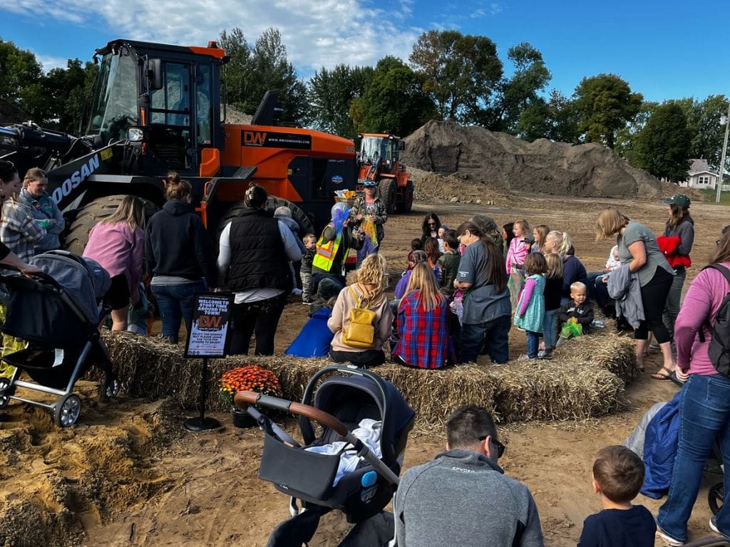 A crowd of people standing around hay bales.