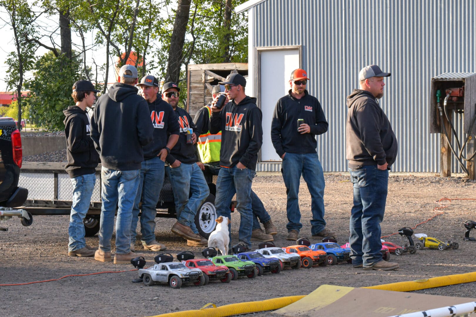 A group of men standing around a pile of toy trucks.