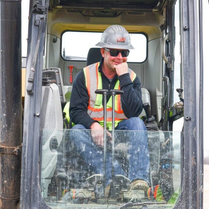 A man sitting in the cab of an excavator.