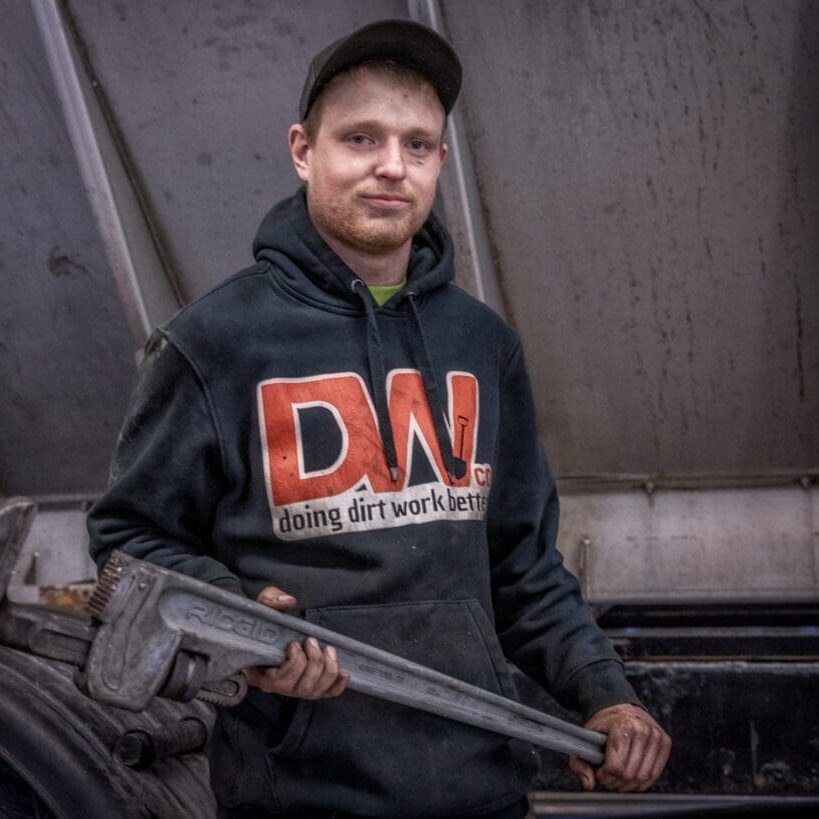 A man holding an adjustable wrench in his hands.